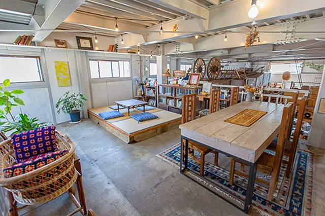 天井が高く広い室内に、木製のテーブルセットや畳の小上がりが置かれています。