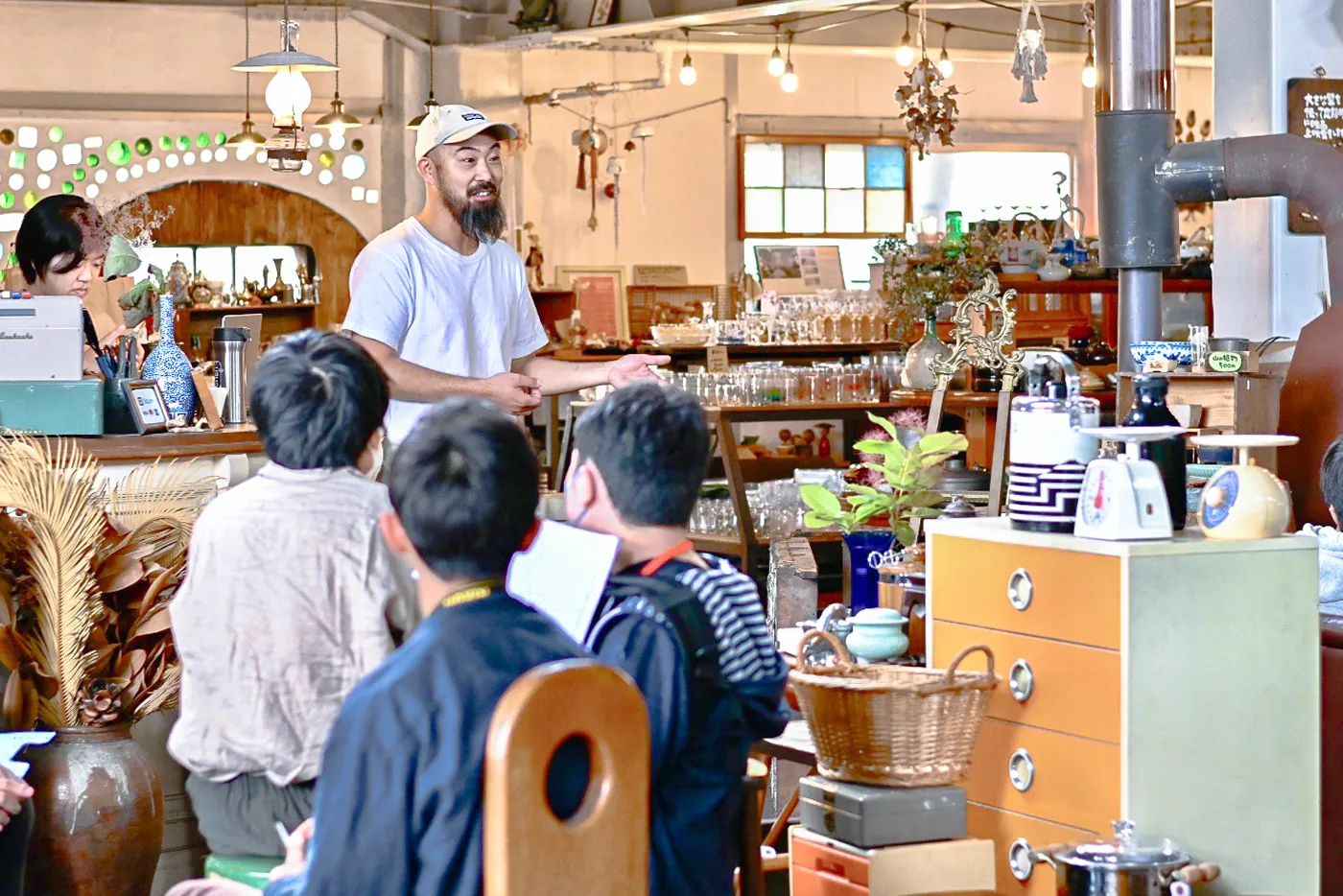 店内の一角で、男性が人々を前に立って話している。参加者たちはその後ろ姿から熱心に聞いているのがわかる。