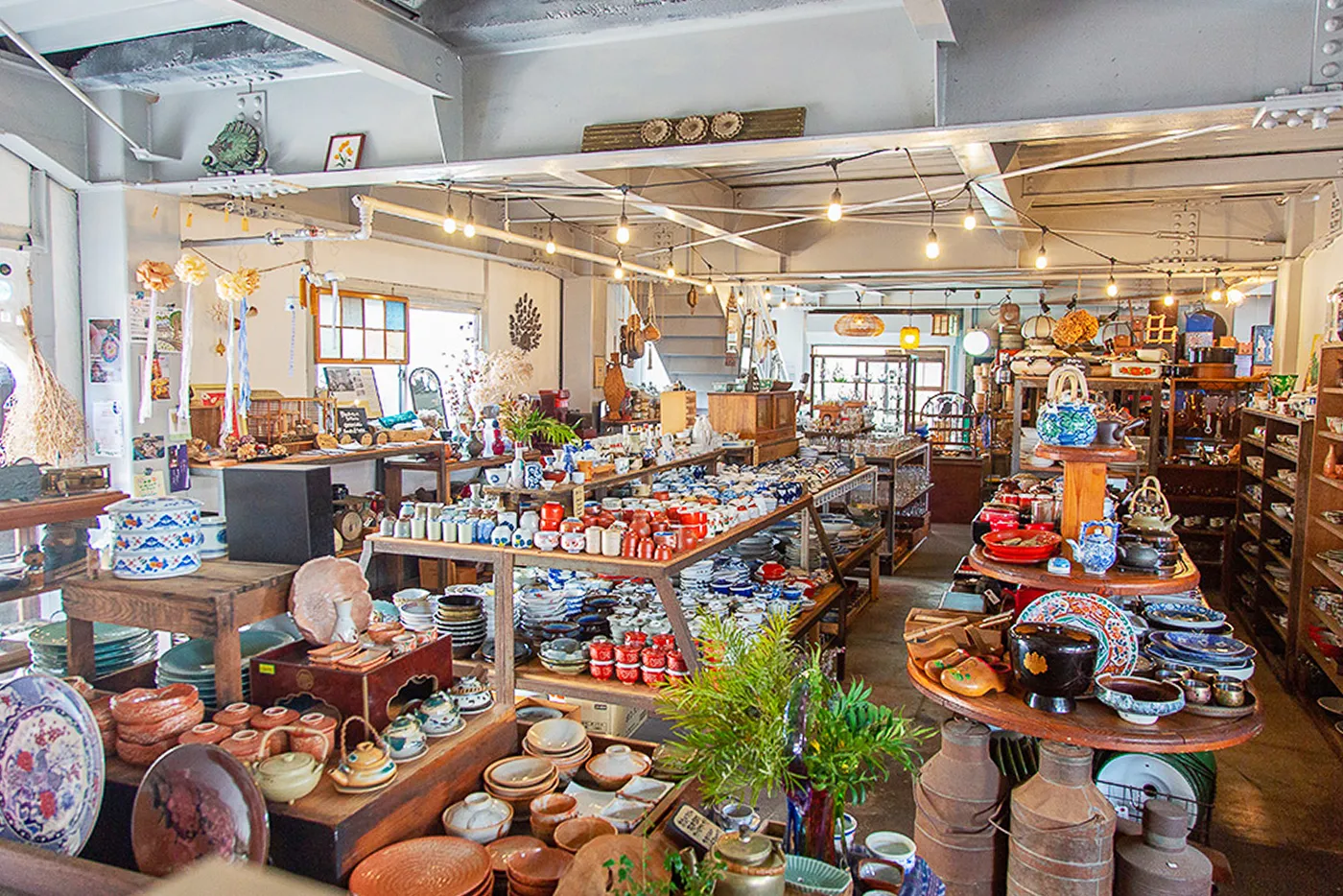 たくさんの陶器や雑貨が並ぶ店の内部。棚やテーブルの上にお皿やお椀などがぎっしりと陳列されている。