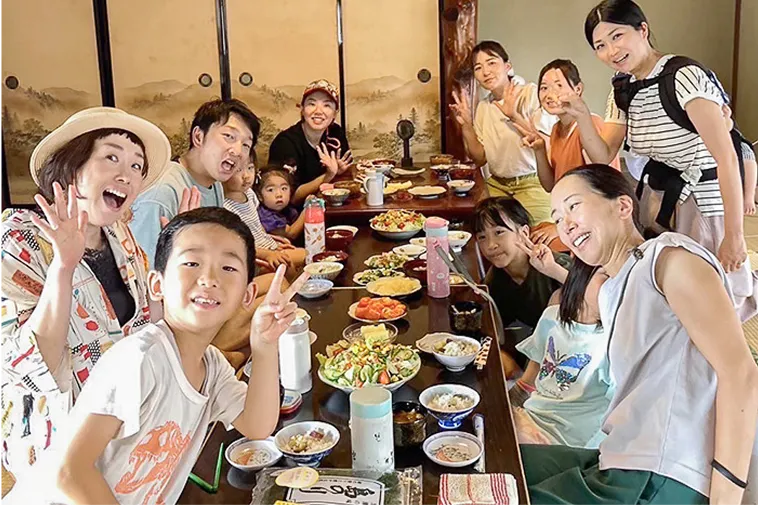 和室で、大人と子供たちが食卓を囲んでいます。皆カメラに向かって笑顔で手を振ったりしています。
